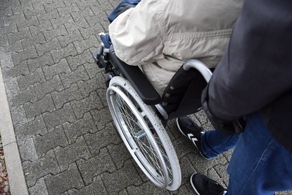 Person schiebt eine andere im Rollstuhl