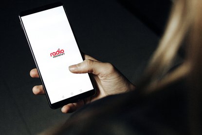 Frau hält Smartphone mit geöffneter Radio Hochstift-App